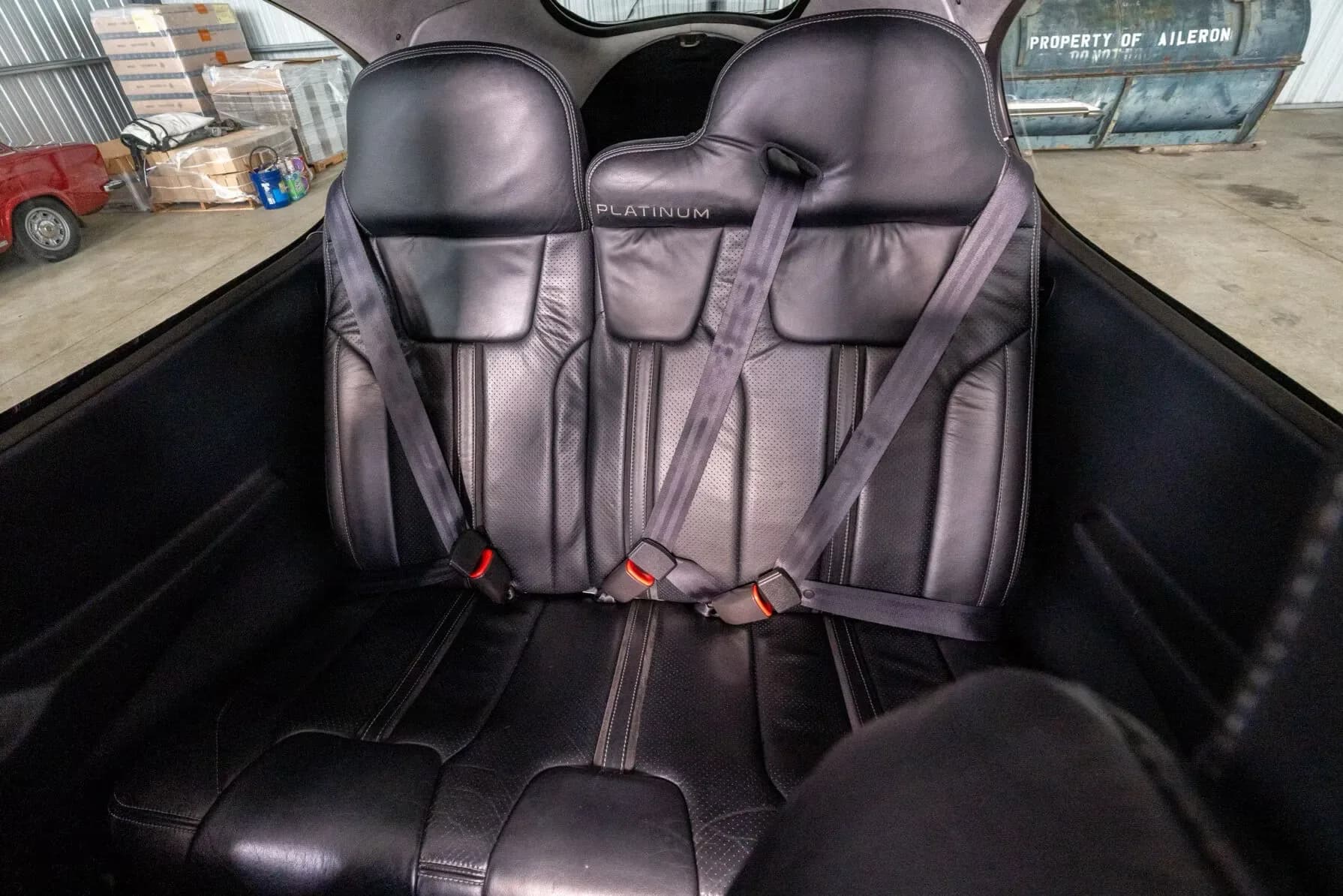 The black leather rear seats of the Cirrus SR22 aircraft cabin, with seatbelts fastened.