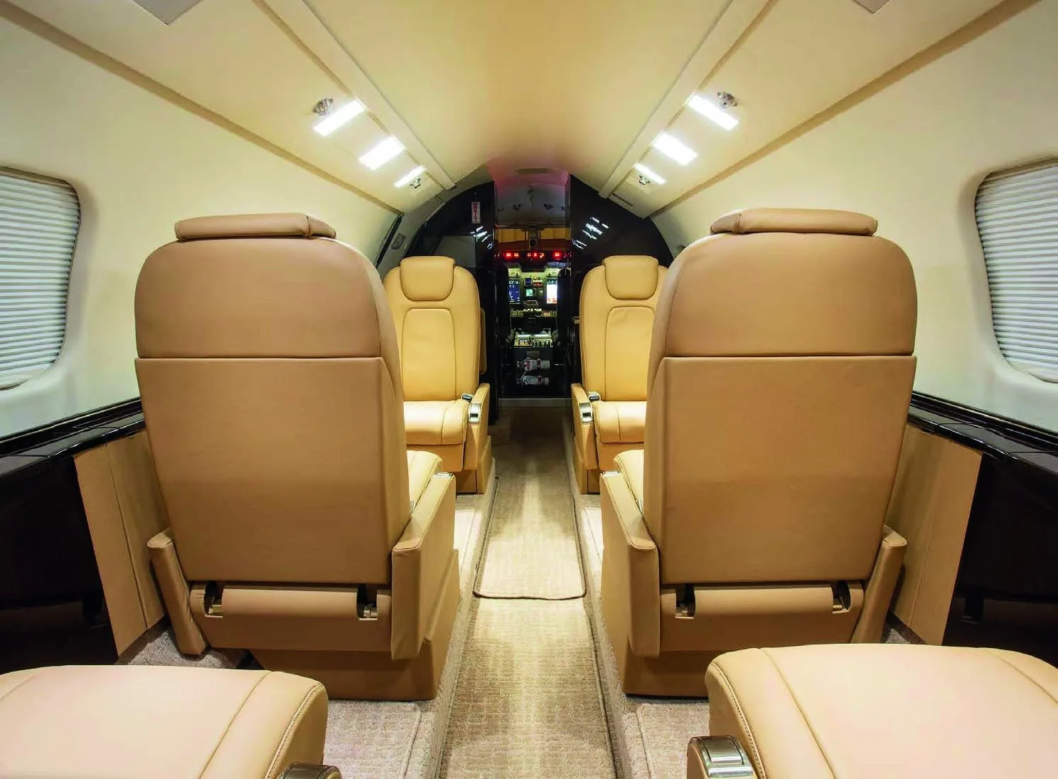 A view down the aisle of a Learjet 75 cabin, showing tan leather seats and overhead lighting.