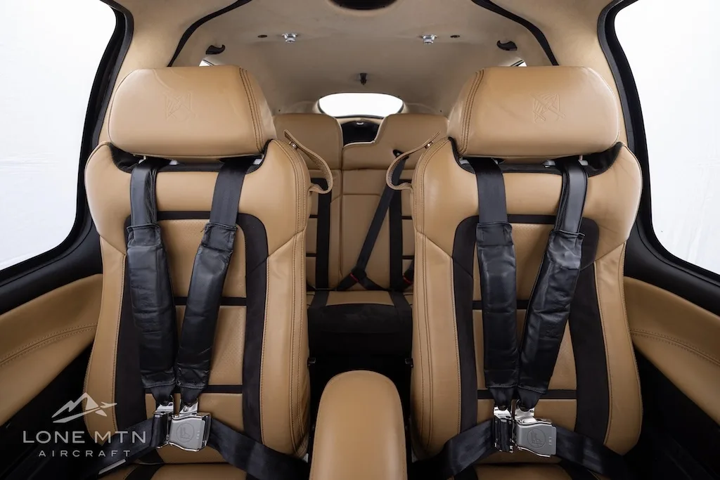 The tan and black leather front seats of the aircraft cabin, viewed from the rear.
