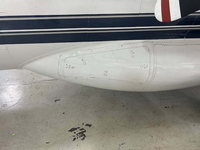 Close up of the side of a white aircraft with black stripes.