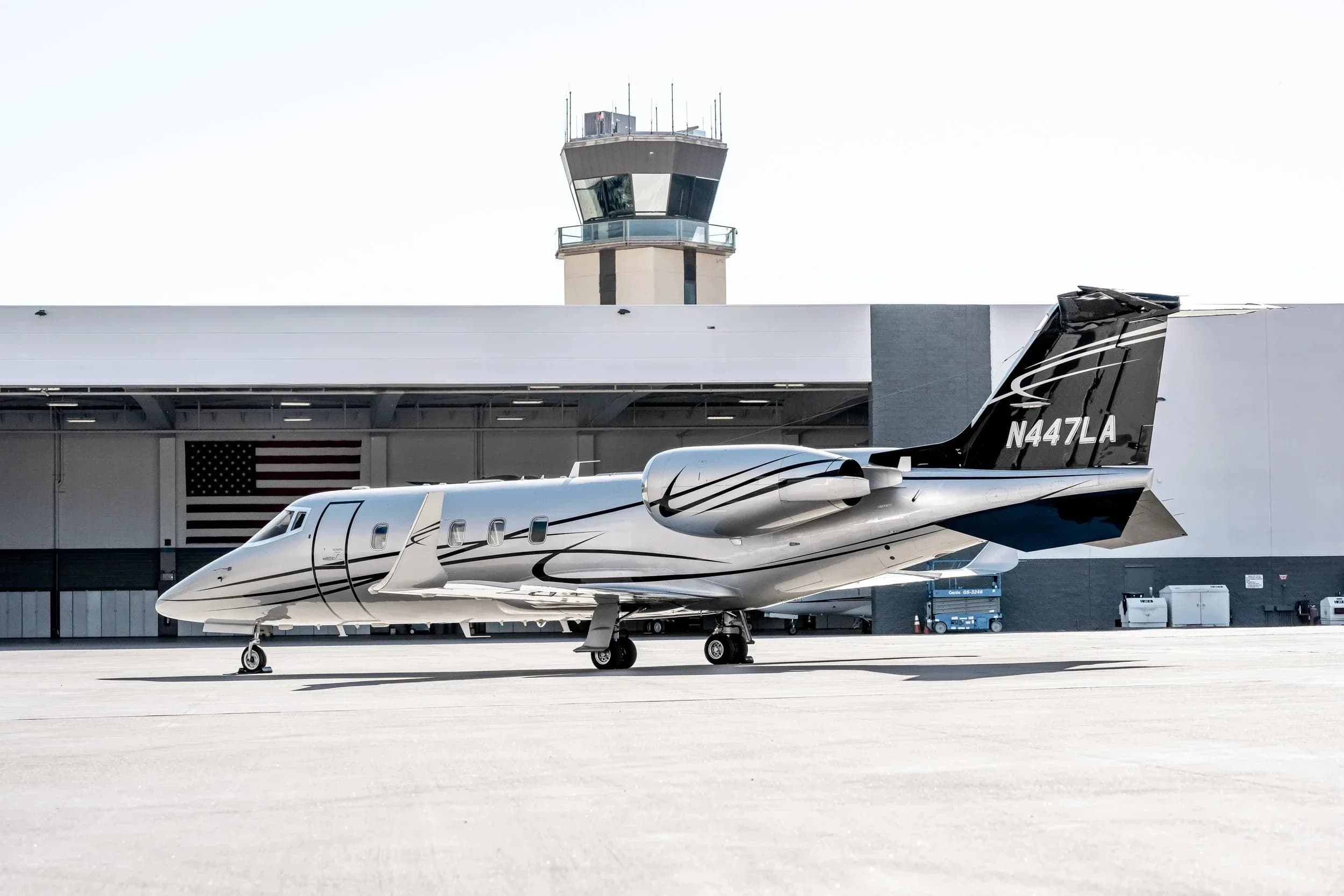 Learjet 45XR, registration N447LA, parked on the tarmac with an airport control tower in the background.