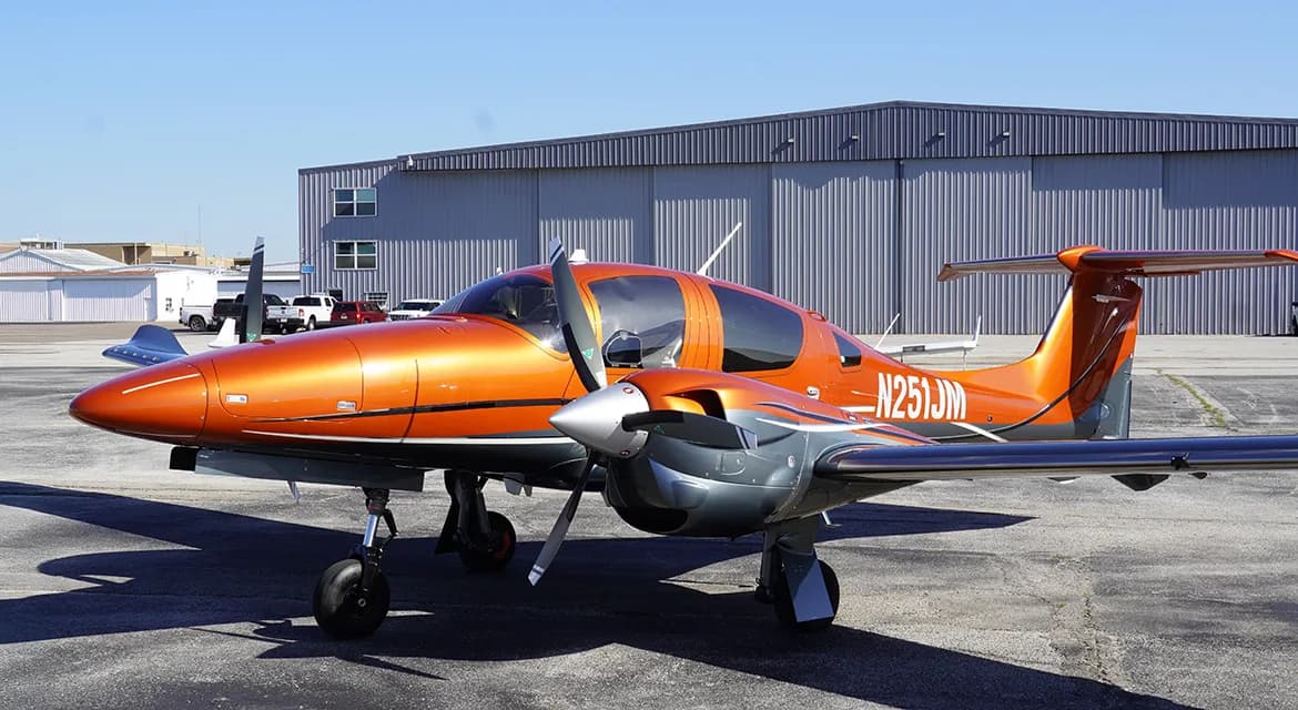 Diamond DA62 aircraft with orange and gray paint scheme parked on the tarmac.