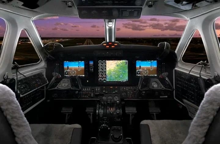 The cockpit of a King Air aircraft with modern avionics and a view of the runway.