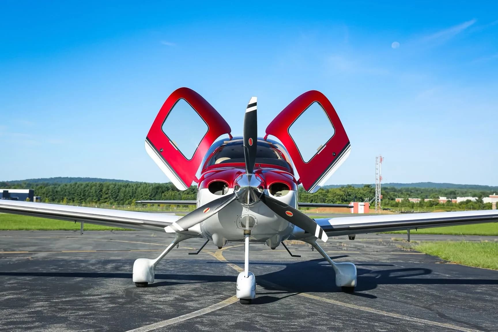 Front view of a red and white Cirrus SR22 aircraft (N412CP) with its doors open, parked on an airfield.