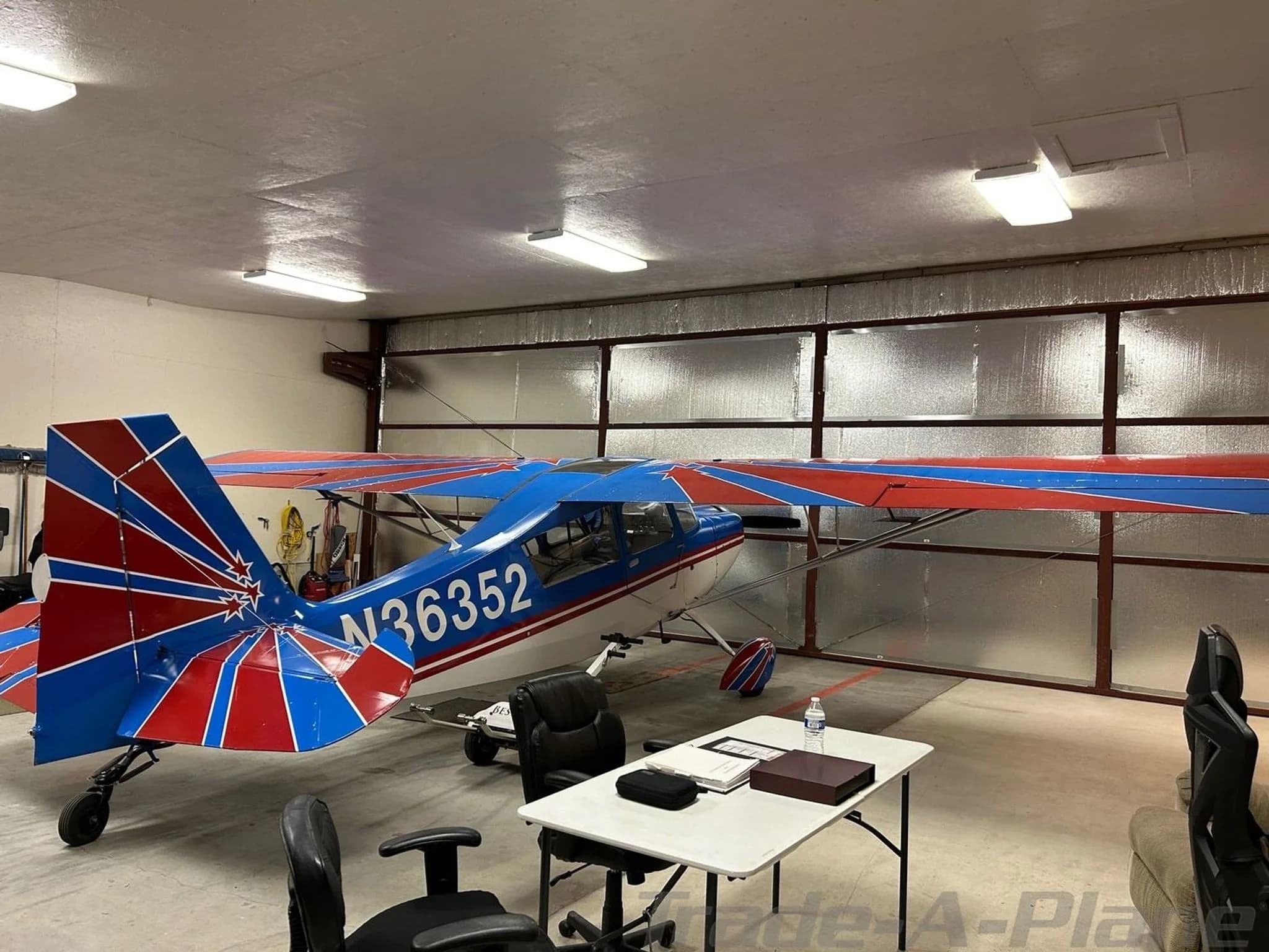 Rear view of a blue and white high-wing aircraft, N36352, with a distinctive red and blue tail, parked in a hangar.