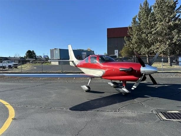 A red and silver LX7 aircraft is parked on the tarmac.