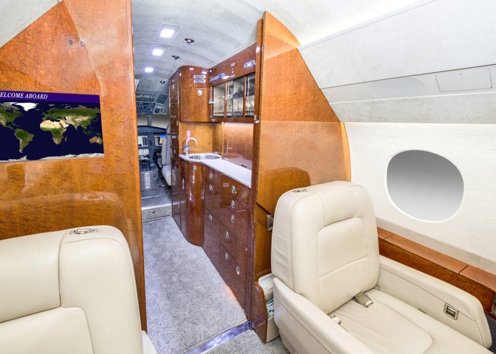 Interior view of the aircraft cabin with leather seats and wood trim.