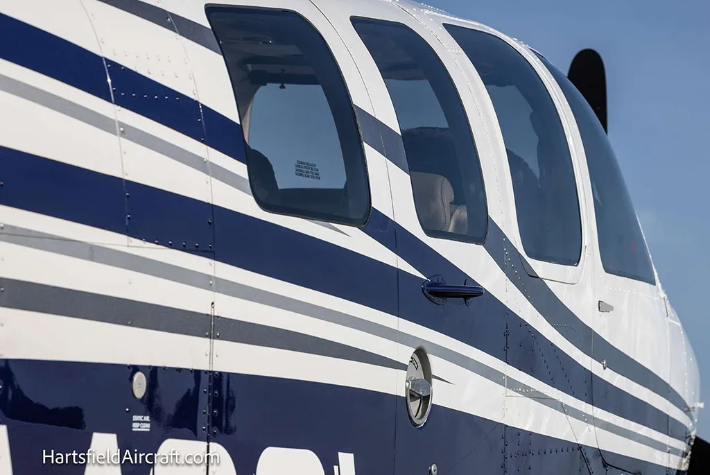 A close-up of the windows and blue and white paint scheme on the side of the Beechcraft Bonanza N4081.