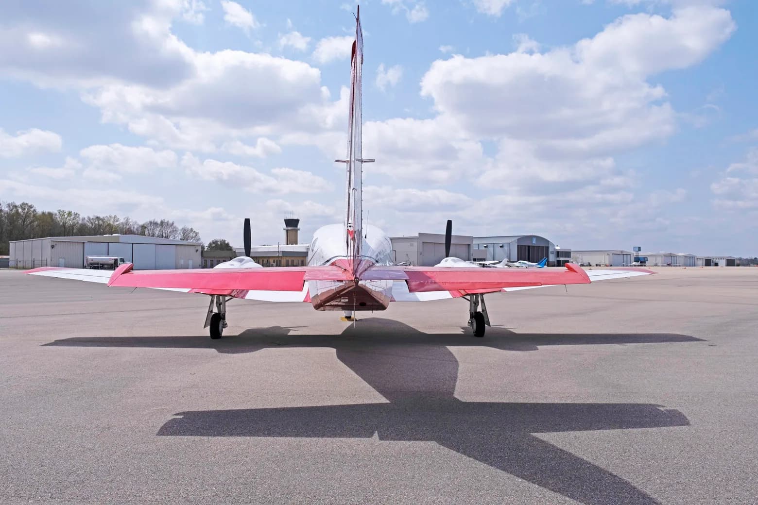 A rear view of a white and red twin-engine propeller aircraft, a Cessna 421C Golden Eagle, parked on an airfield.
