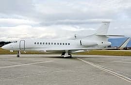 A white private jet parked on a runway.