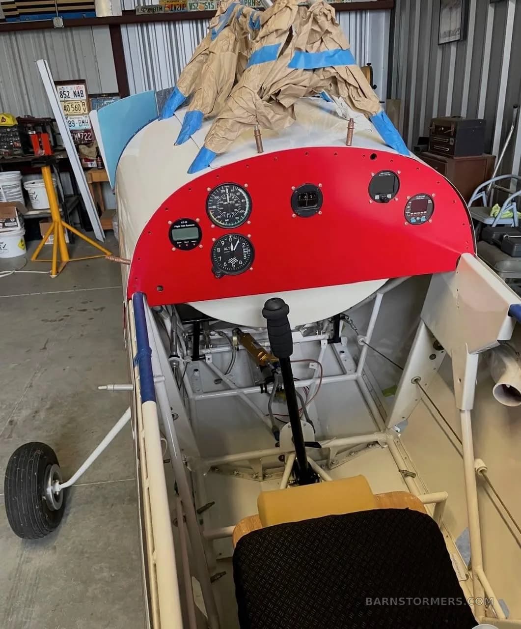 An overhead view of the red instrument panel and open cockpit area of the Pitts Special.