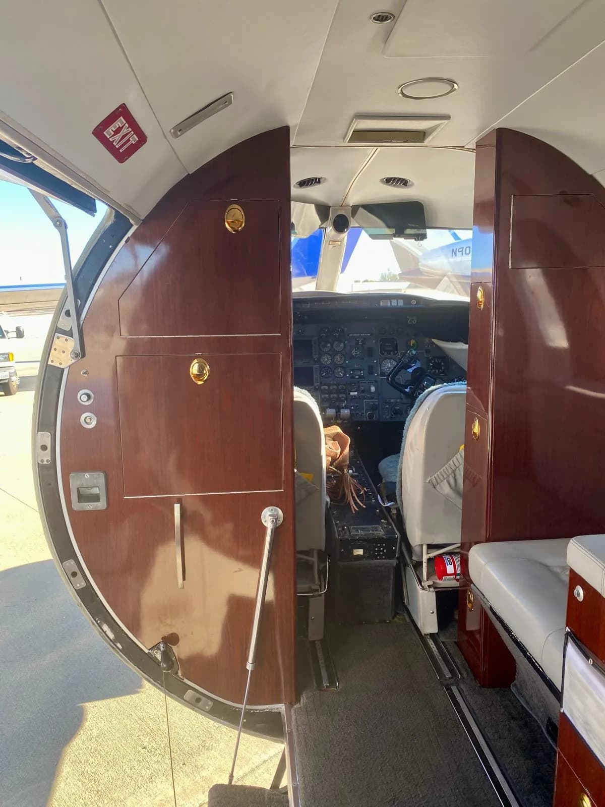View from the aircraft entrance looking into the cabin and open cockpit, showing wood paneling and instruments.
