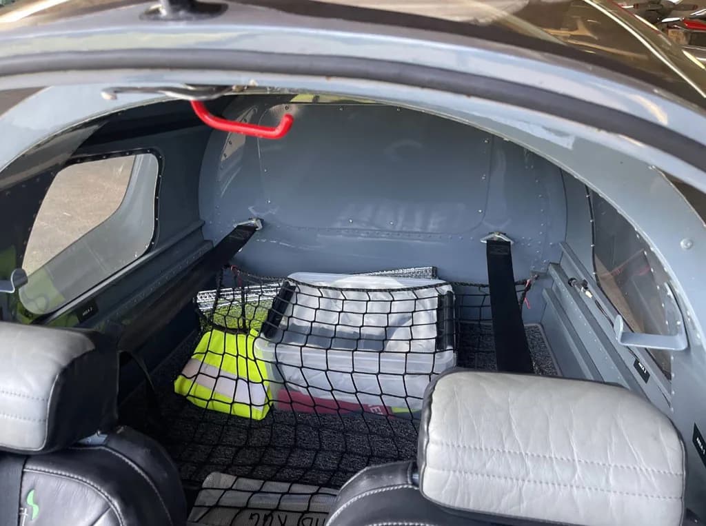 The baggage compartment behind the seats of the aircraft, secured with a net, is shown.