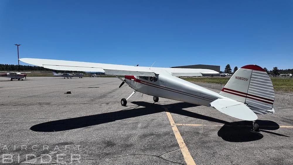 A rear quarter view of a white 1950 Cessna 170A aircraft (N3835V) with red accents, parked on an airfield.