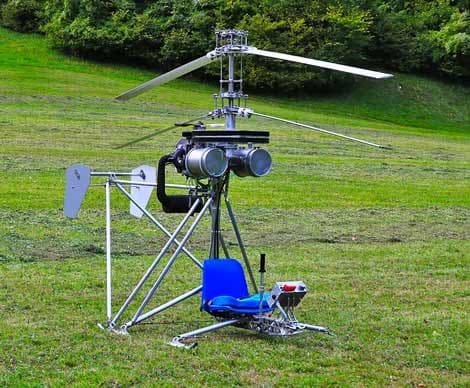 A single-seat helicopter sitting on a grassy field.