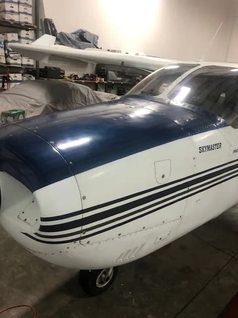 Close up of the front of a blue and white Cessna Skymaster in a hangar.