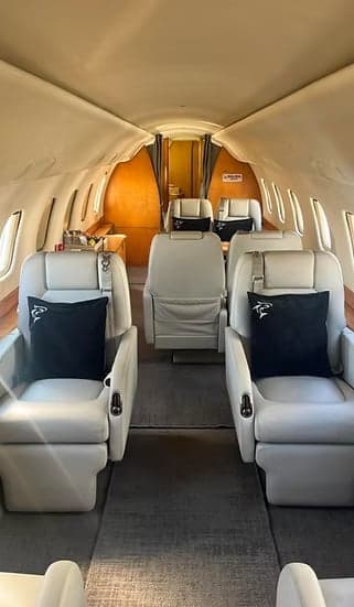View of the interior cabin of the aircraft with white leather seats.