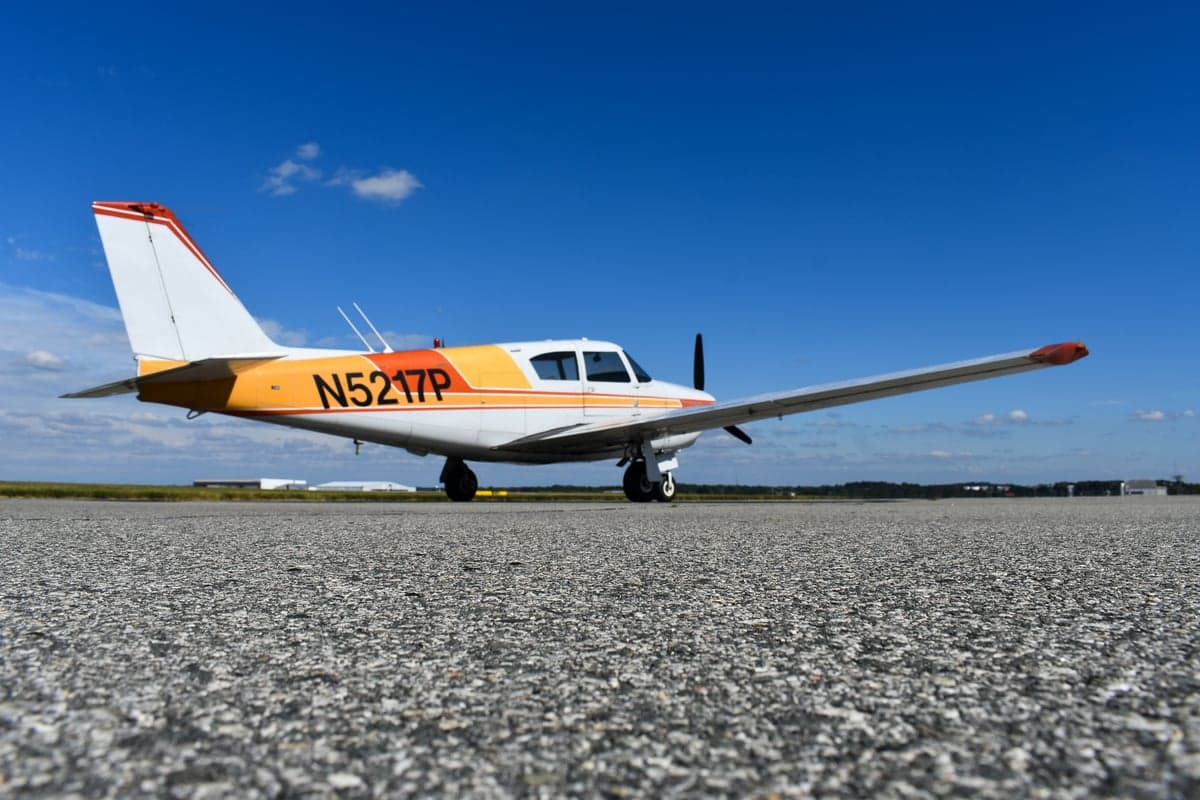 Piper Comanche 250 aircraft, front view, on the tarmac.