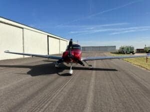 Front view of a Cirrus SR22T aircraft on a tarmac with a hangar in the background.