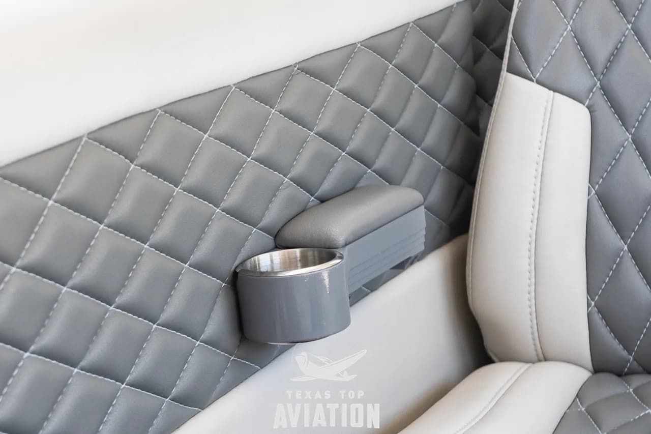 A close-up of the quilted grey side paneling and a cup holder in the aircraft's interior.