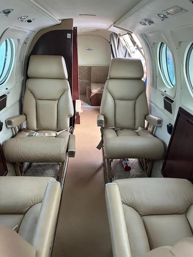 The interior cabin of an aircraft, showing two rows of tan leather passenger seats facing each other.