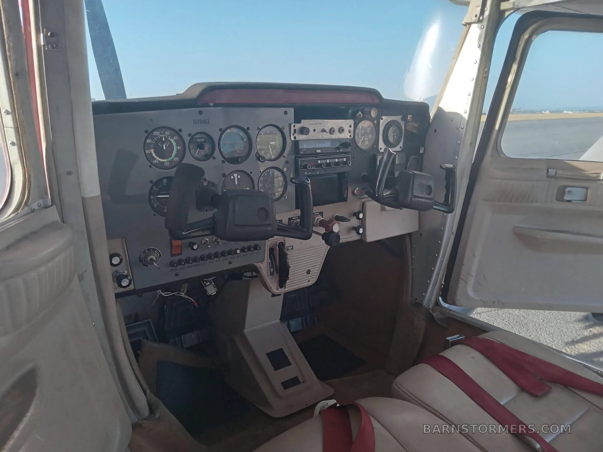 The cockpit of a light aircraft, showing the instrument panel, yokes, and front seats.