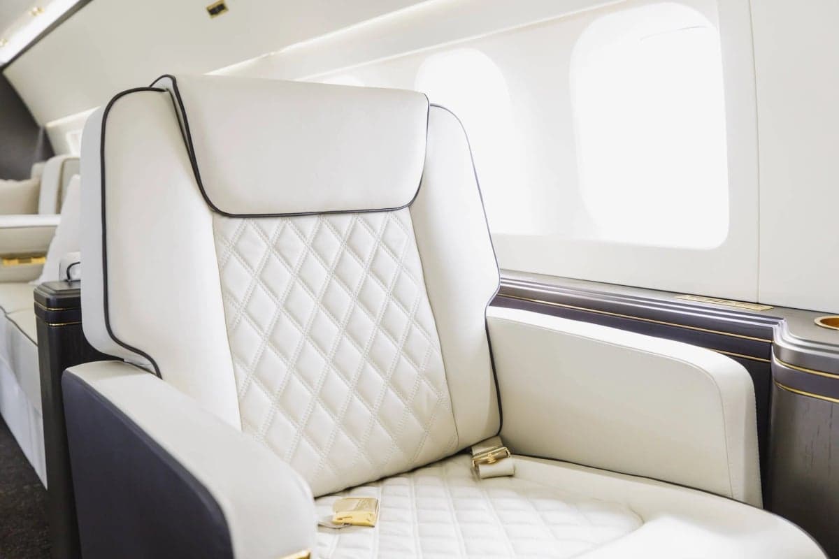 Close-up of a white leather seat with diamond stitching and dark wood trim.