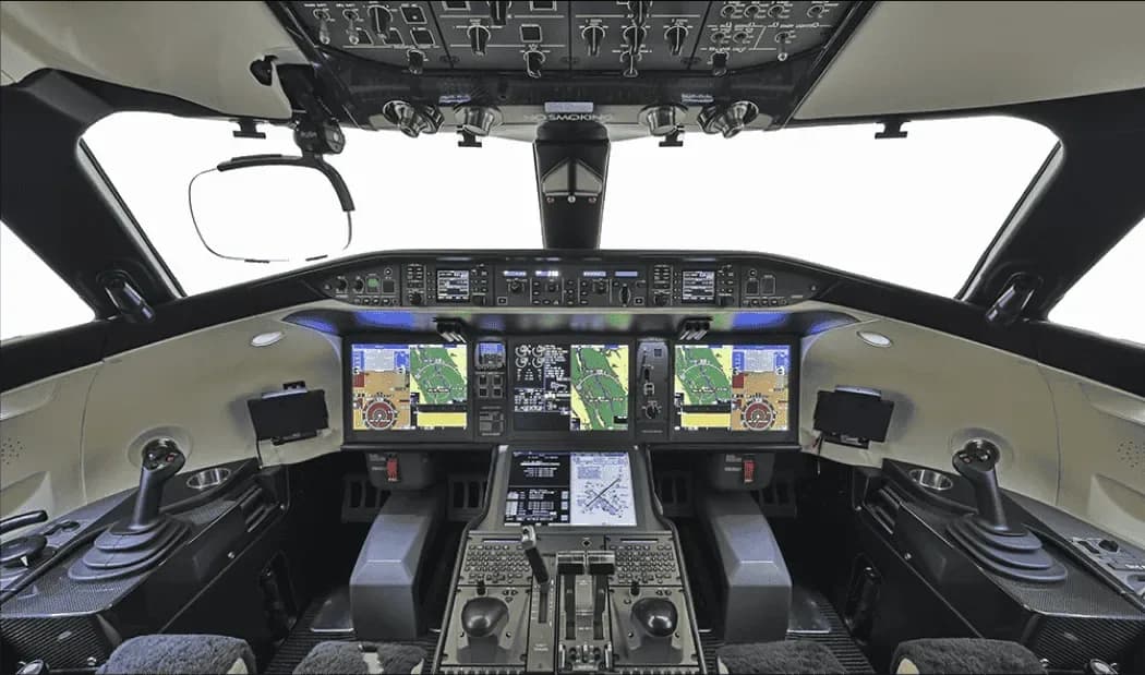 The modern cockpit of a business jet, featuring multiple large digital displays and advanced controls.