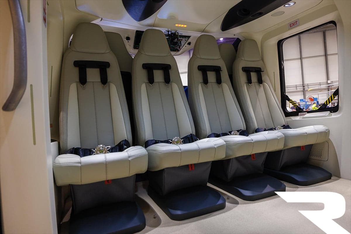 Four light grey passenger seats with dark seatbelts in the cabin of an Airbus H160 helicopter.
