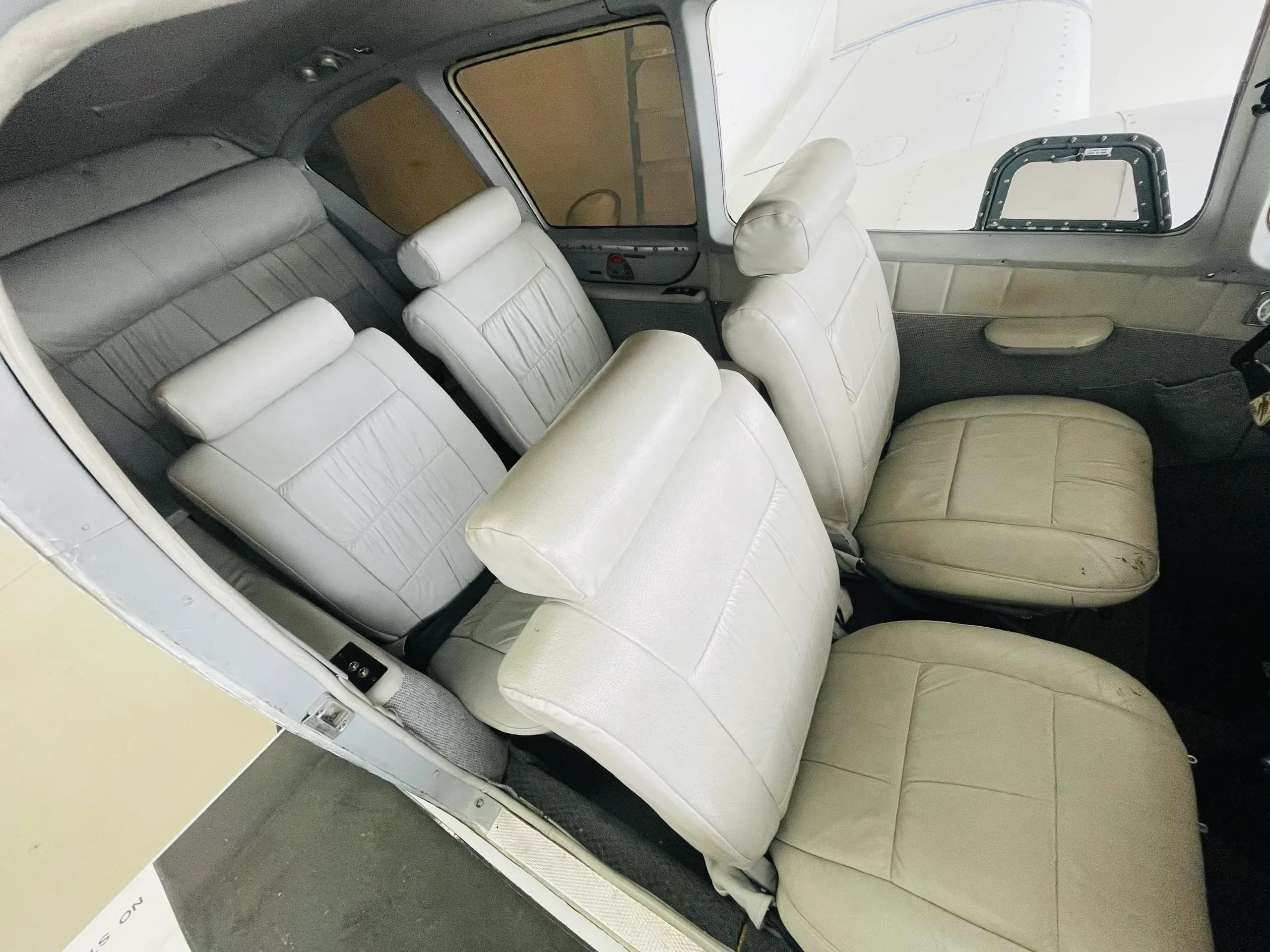The aircraft's cabin interior features multiple rows of white leather passenger seats.