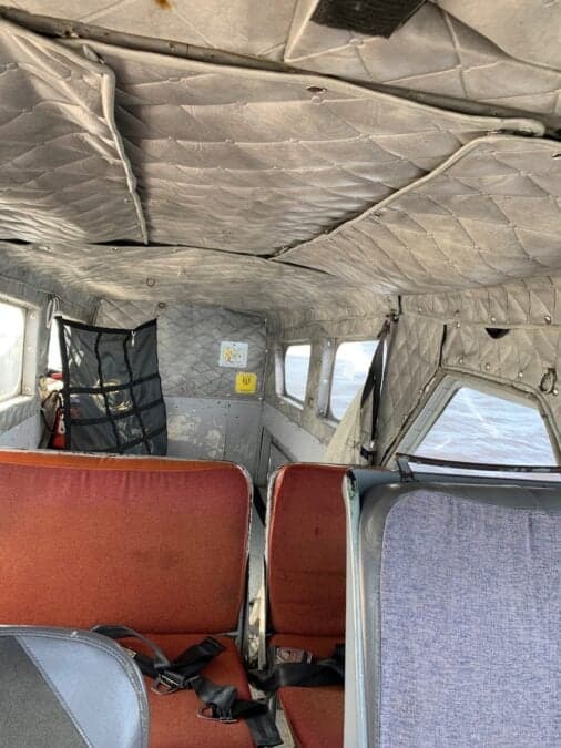 The interior of the aircraft shows the seats and quilted ceiling.