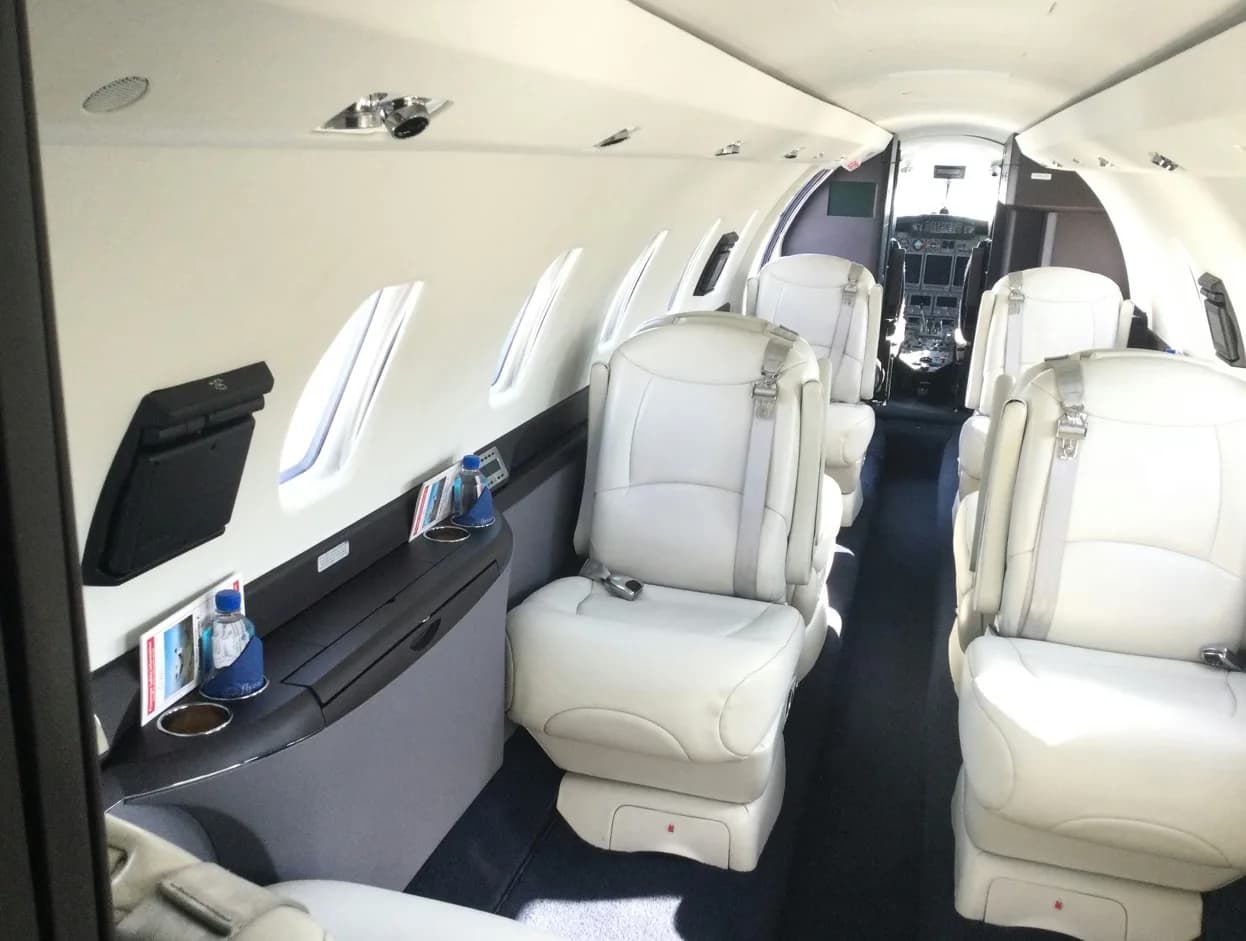 Aircraft cabin with light gray leather seats and a view towards the cockpit.
