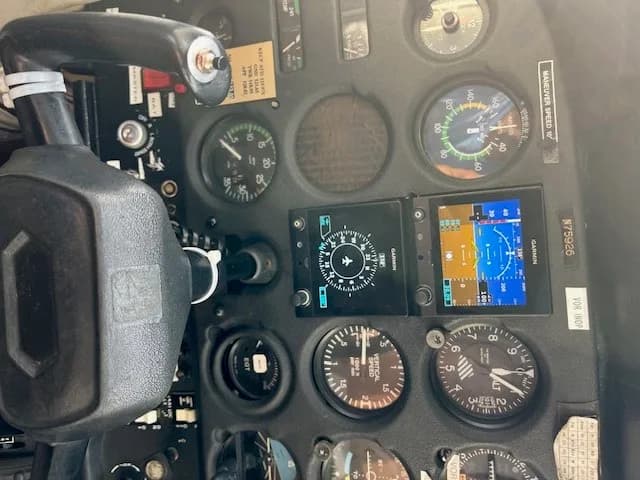 Close-up of the cockpit instrument panel with a yoke, analog gauges, and digital displays.