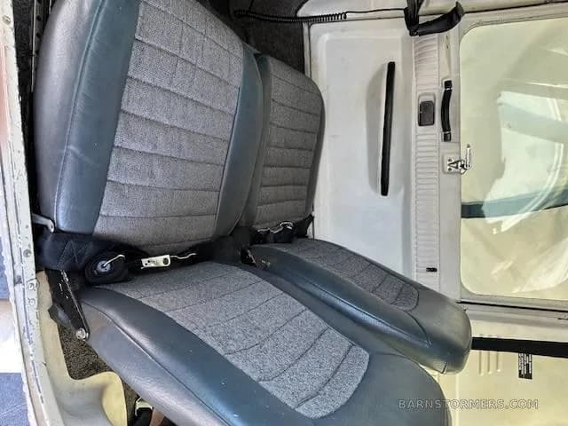 Two grey fabric and leather aircraft seats with seatbelts are visible in the cabin.