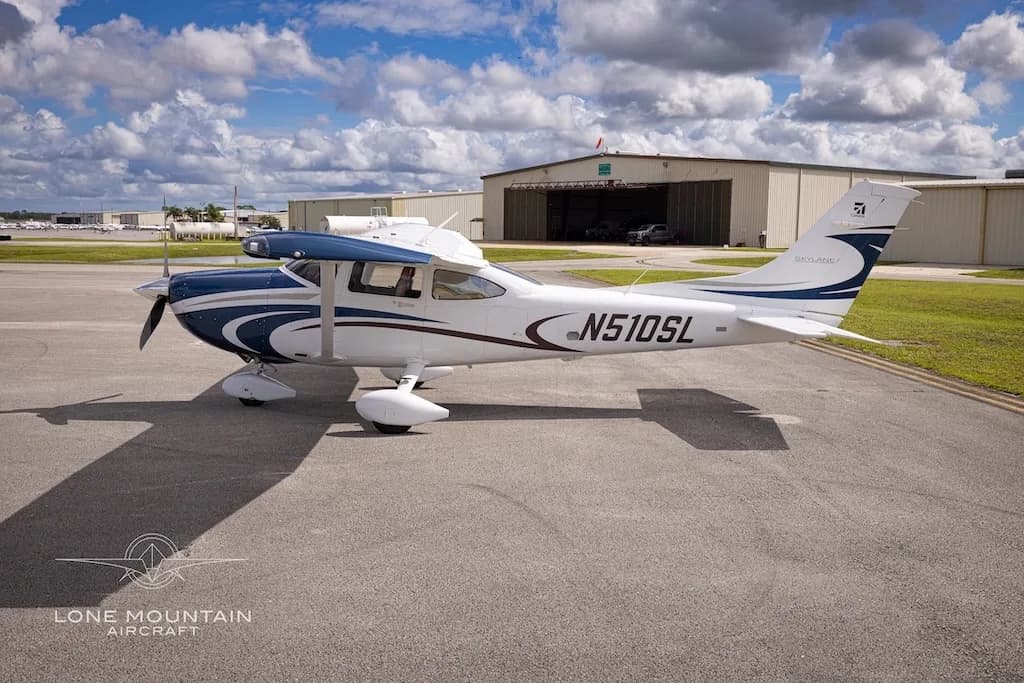 A three-quarter front view of the white and blue Cessna 182 Skylane aircraft, N510SL, parked on an airfield.