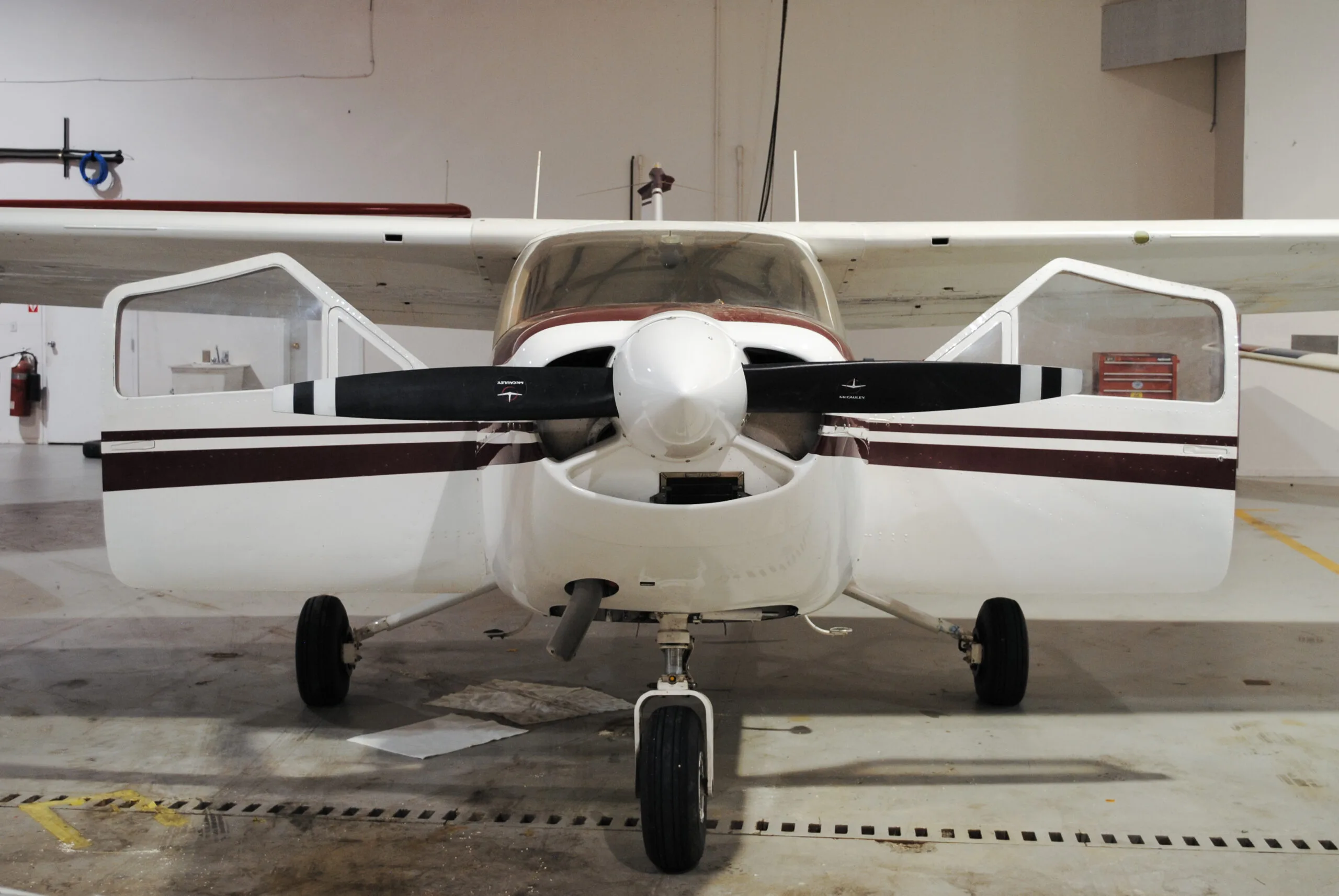 Front view of a Cessna 177 Cardinal with open doors, showing the propeller and landing gear.