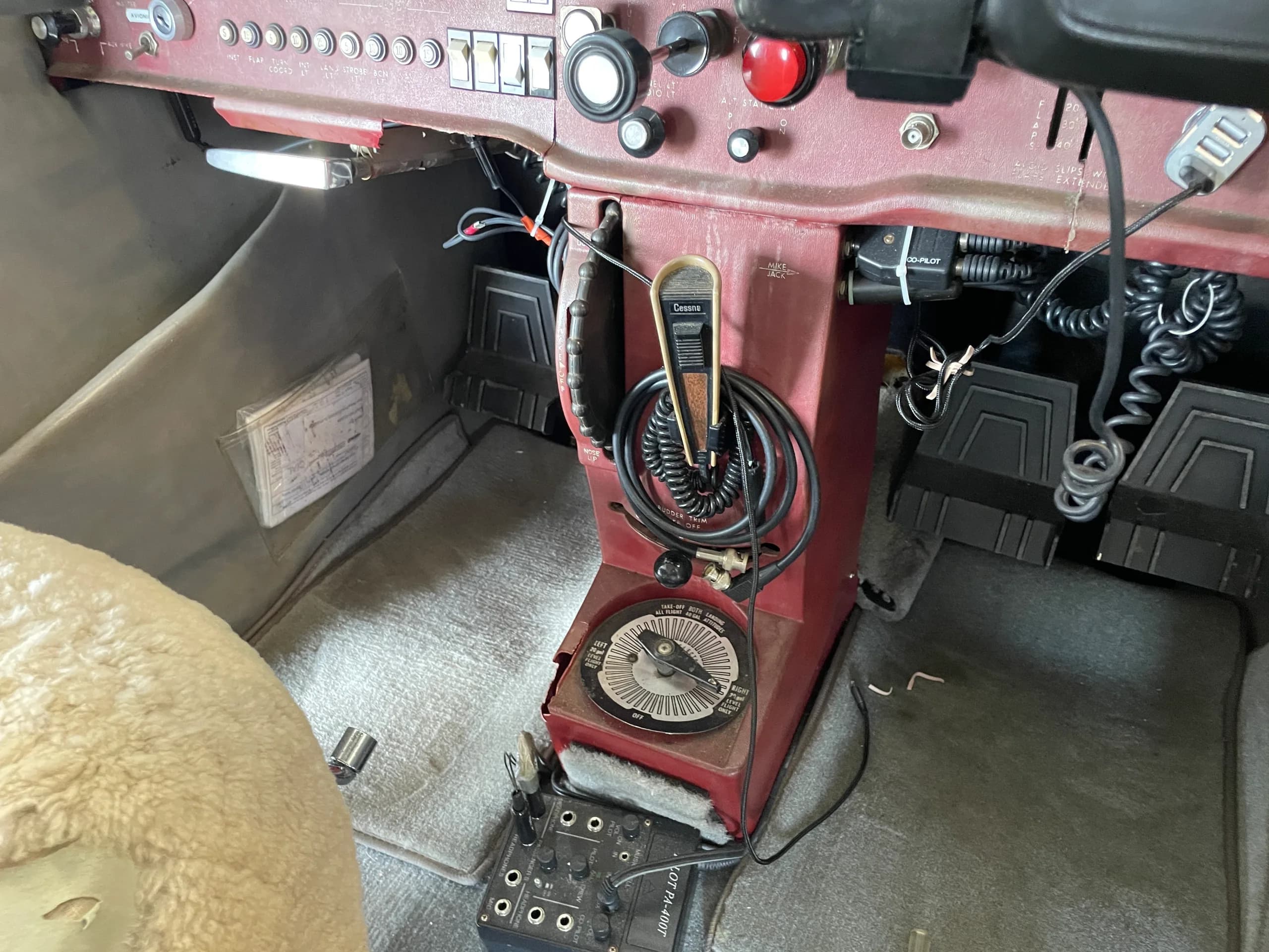 A view of the lower center console and floor of a Cessna 172 cockpit, showing pedals and a microphone.