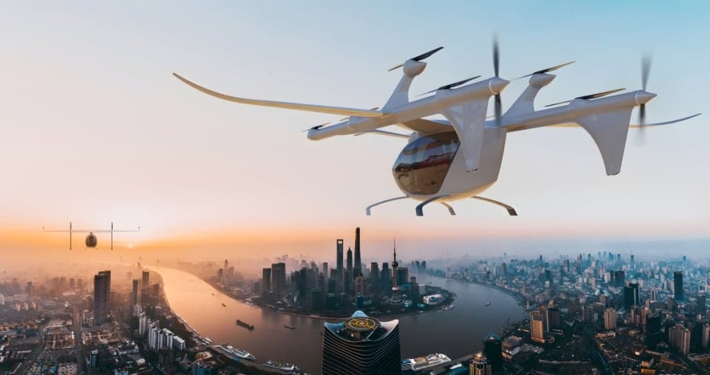 A rendering of an eVTOL aircraft flying over a city skyline at sunset.
