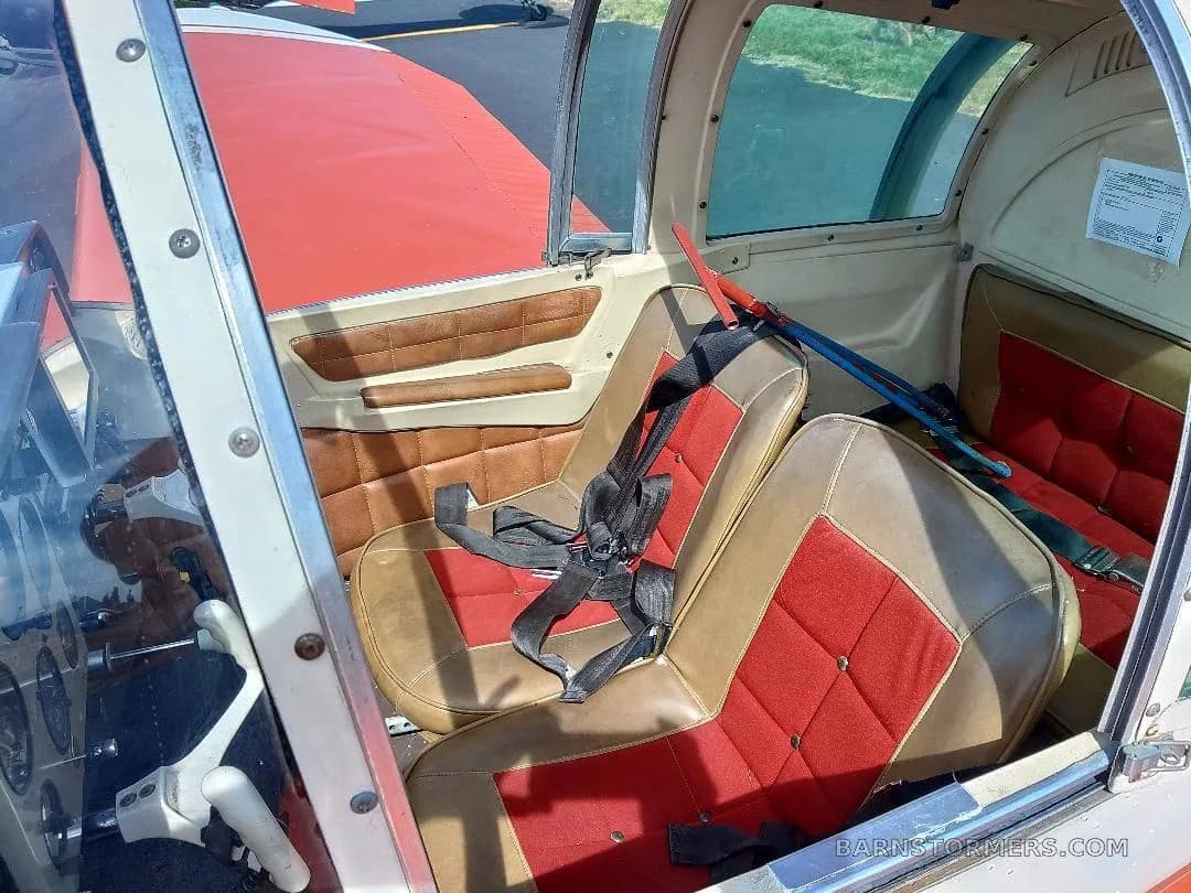 The aircraft's interior features two-tone red and tan seats with seatbelts.