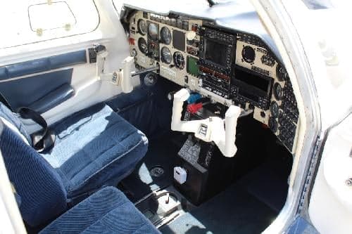 The cockpit of the aircraft with blue seats and a white control panel.