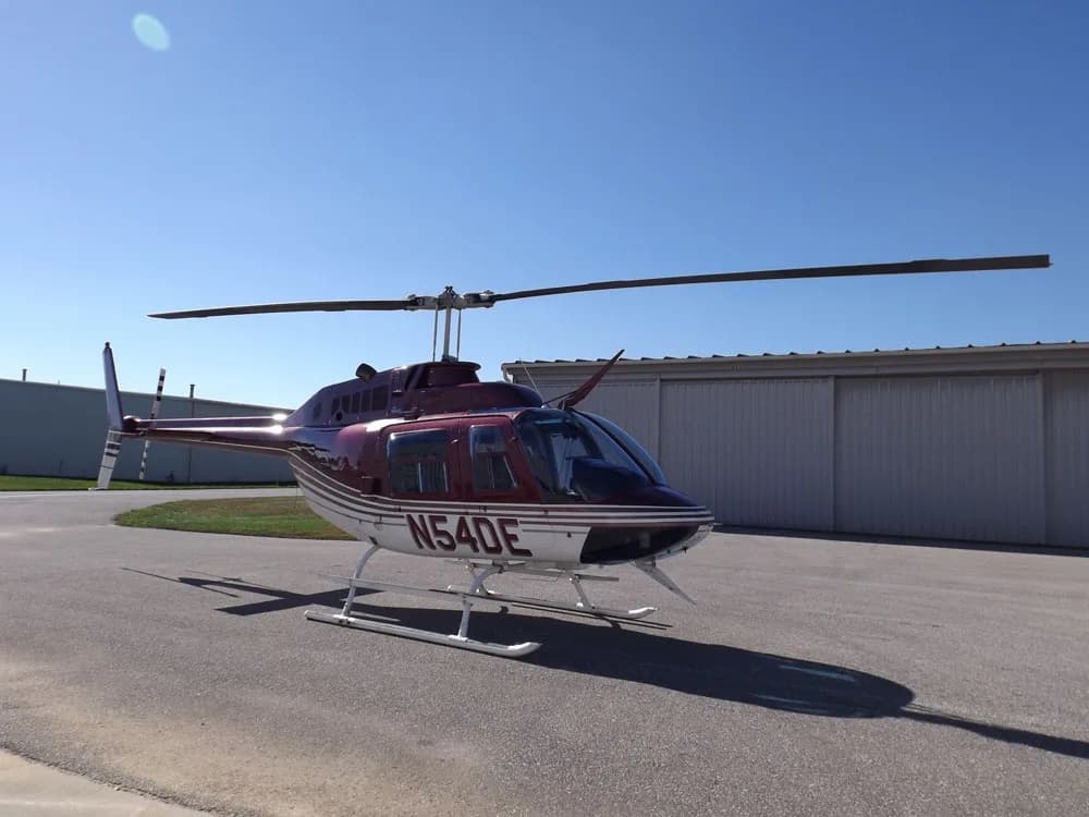 A Bell 206B JetRanger III helicopter with registration N54DE is parked on the tarmac.