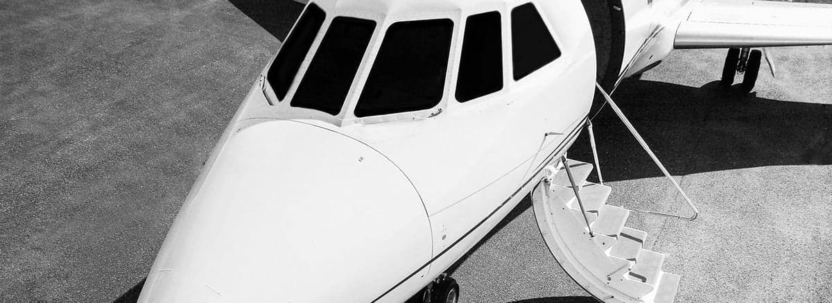 Close up of the front of a white jet with airstairs extended.