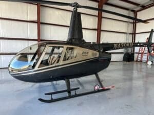 A side view of the Robinson R66 helicopter, registration N430KM, shows its black and gold paint scheme.
