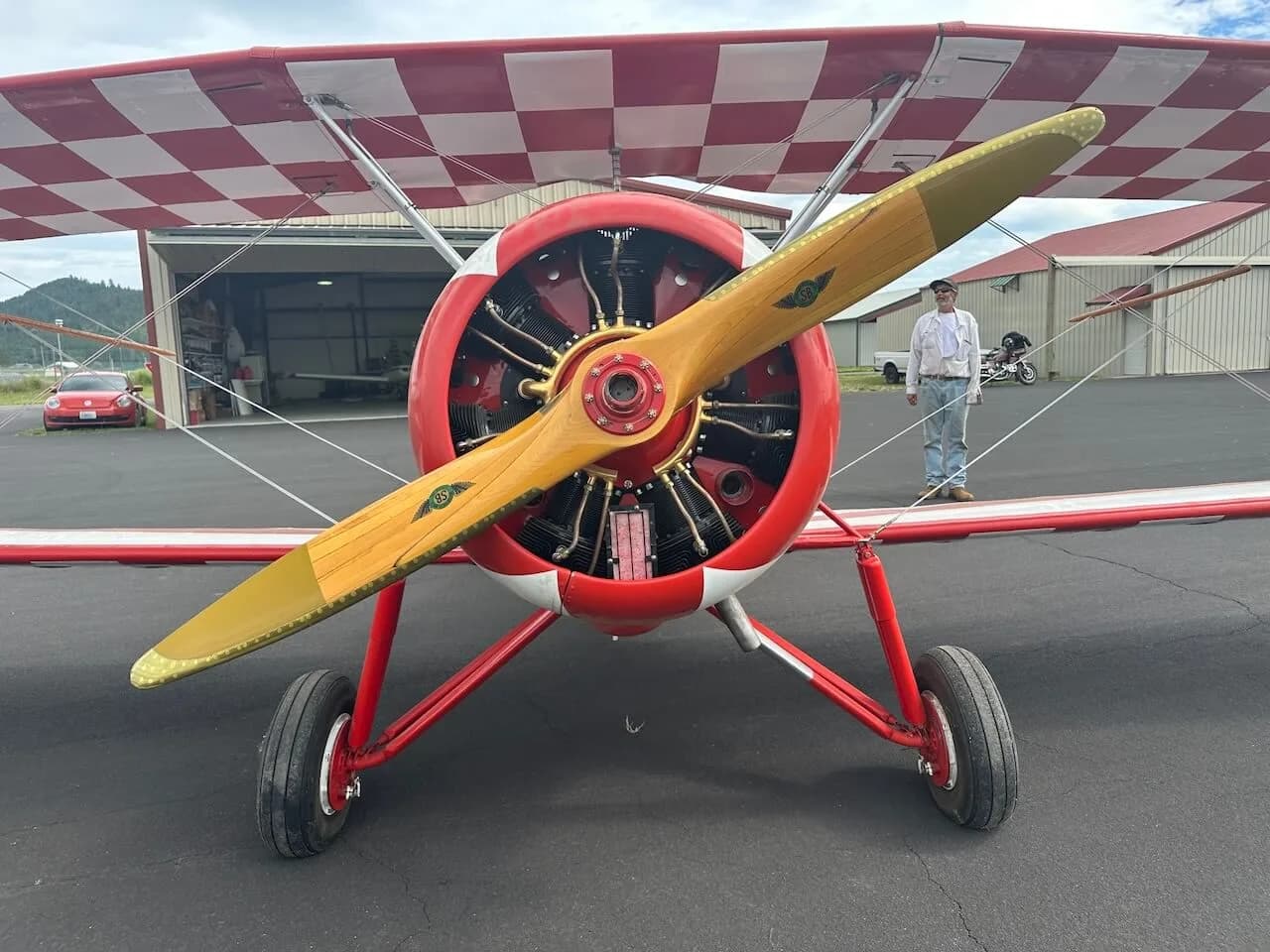 A front view of the red biplane, highlighting its wooden propeller and radial engine.
