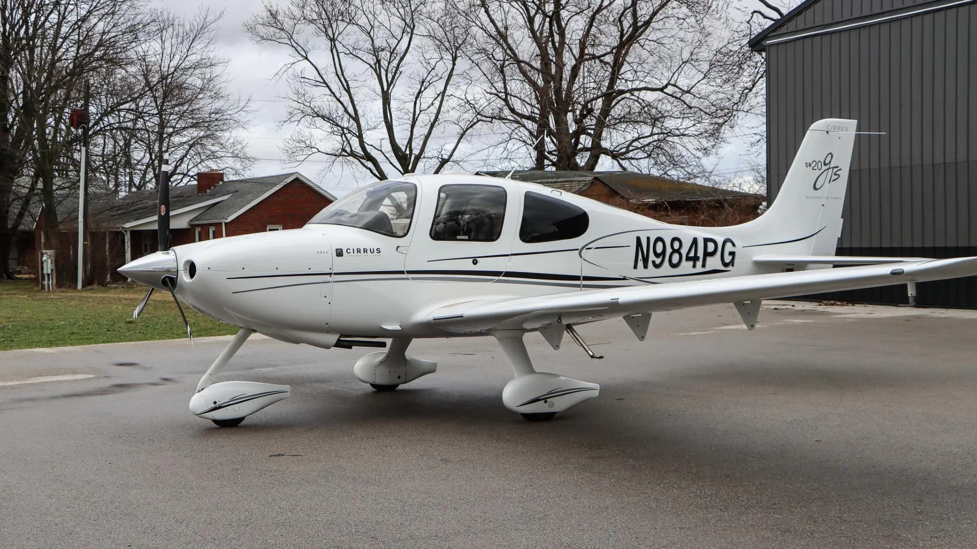 A white Cirrus SR20 GTS aircraft, N984PG, is parked with its right side visible, showing the registration number.