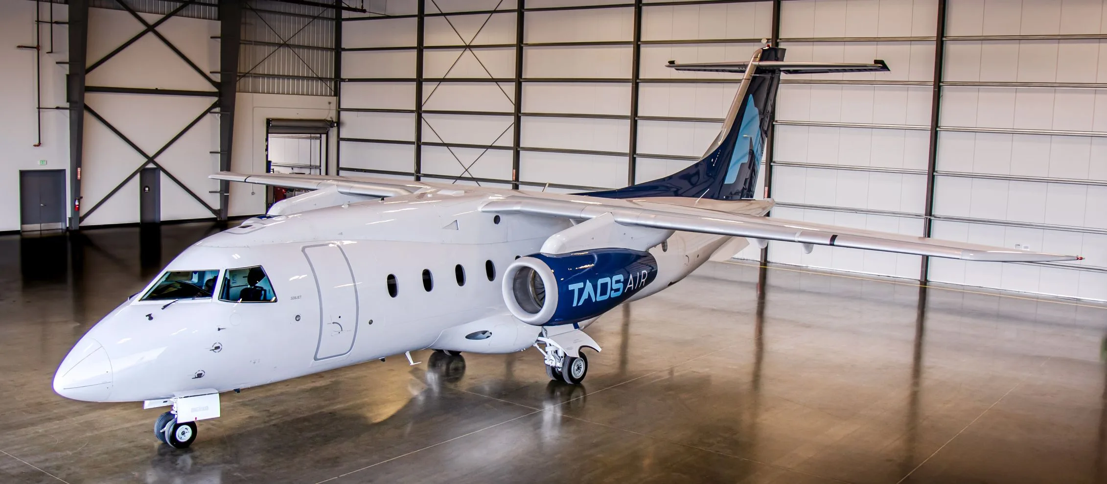 A TADS Air jet is parked inside a hangar.