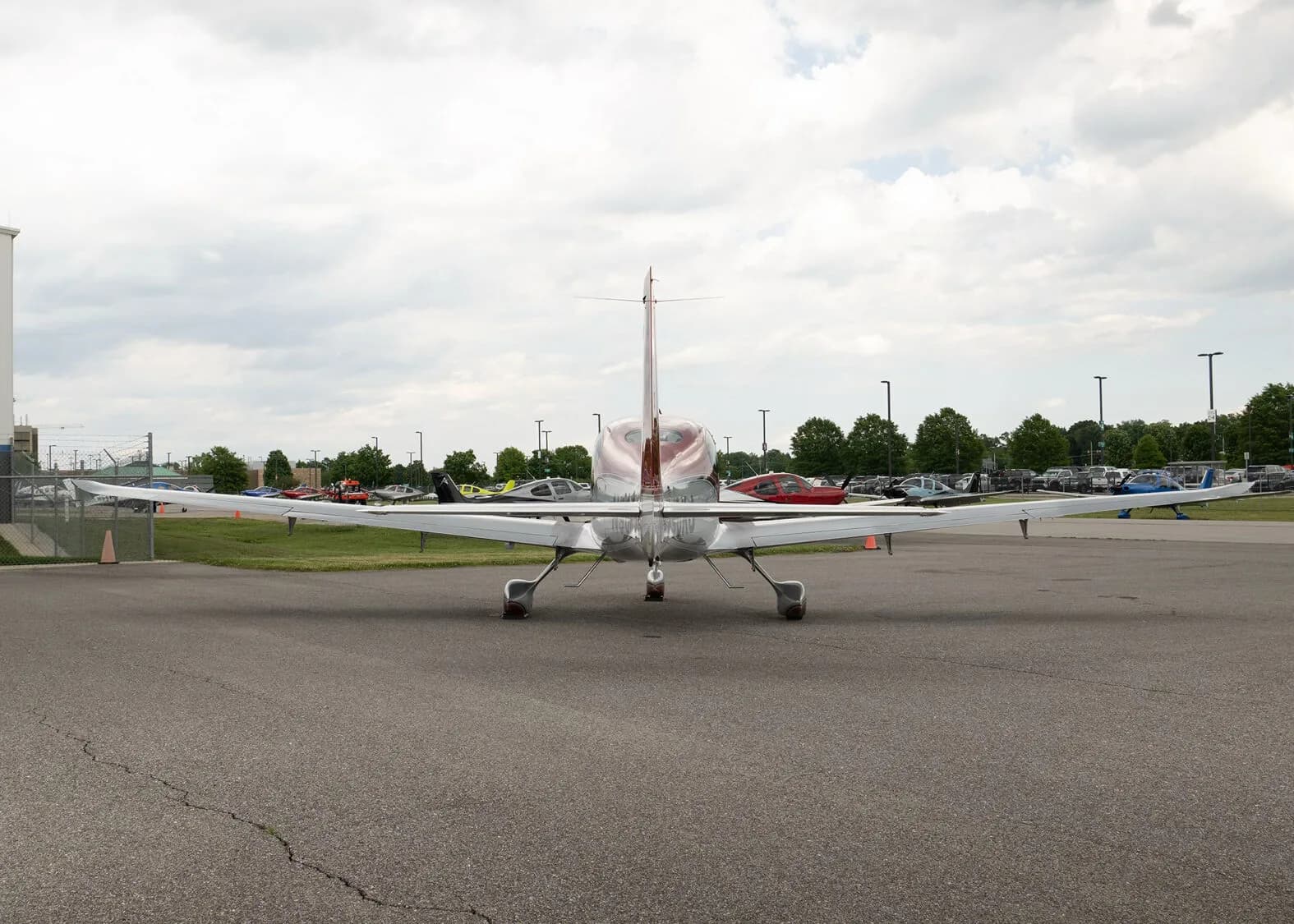 A rear view of a red and silver Cirrus SR22T aircraft, registration N96KJ, parked on an asphalt apron with other aircraft in the distance.