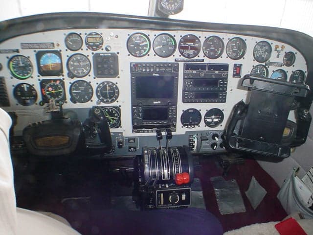 The cockpit of a twin-engine aircraft, showing the instrument panel with various gauges, avionics, and control yokes.