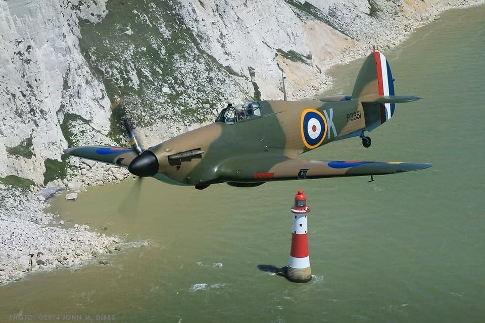Hawker Hurricane fighter parked on a grassy field, side view.