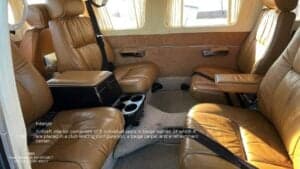 The interior of a Piper Seneca III PA-34-220T aircraft, featuring leather seats and a club seating configuration.